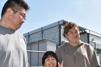 仮設住宅団地集会所で講演を終え、ヒマワリを手にポーズをとる菊地良さん（中央）を愛おしそうに見つめる 父修さんと母いつかさん＝石川県七尾市で、2026年5月2日午後2時31分、中尾卓英撮影