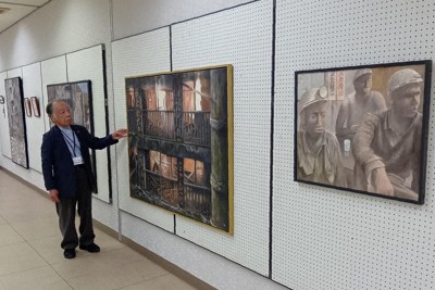 展示のメインの軍艦島シリーズの一部と、作者の落水保之さん＝名張市元町のリバーナホールで2026年5月4日午前11時53分、山口敬人撮影