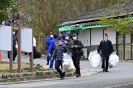 観光地「るり渓」の公衆トイレ周辺の検証現場から出てくる京都府警の捜査員ら＝京都府南丹市園部町大河内で2026年4月18日午後1時37分、資野亮太撮影