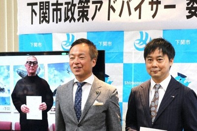 下関市政策アドバイザーの委嘱状を受け取り、前田晋太郎市長（中央）と記念撮影に臨む吉田悟氏（右）と榊原隆之氏（左側の画像モニター内）＝山口県下関市南部町で2026年5月1日午前10時8分、山本泰久撮影