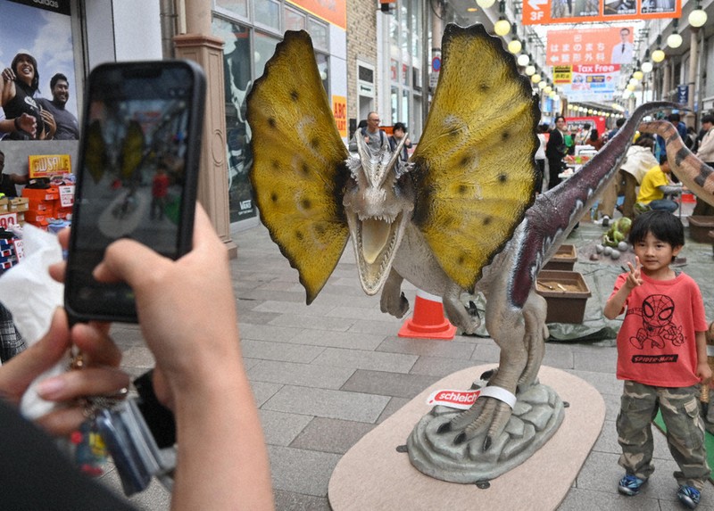 恐竜の模型と写真を撮ってもらう子供＝長崎市浜町で2026年5月5日午後0時57分、百田梨花撮影