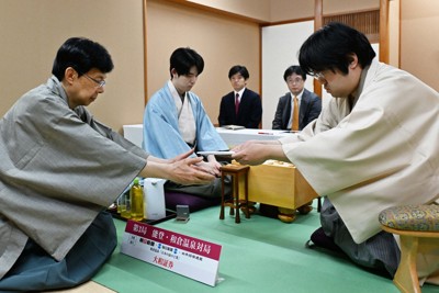 第84期名人戦七番勝負第3局1日目、立会の谷川浩司十七世名人（左）に封じ手を渡す挑戦者の糸谷哲郎九段（右）。奥は藤井聡太名人＝石川県七尾市ののと楽で2026年5月7日午後6時37分、小関勉撮影