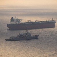 イラン港湾に向かっているとされる船舶の付近を航行する米海軍の艦船（手前）＝米中央軍提供・ロイター
