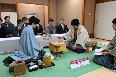 第84期名人戦七番勝負第3局2日目で、立会の谷川浩司十七世名人（右手前）が示した封じ手を見る藤井聡太名人（左）。中央は挑戦者の糸谷哲郎九段＝石川県七尾市ののと楽で2026年5月8日午前9時、小関勉撮影