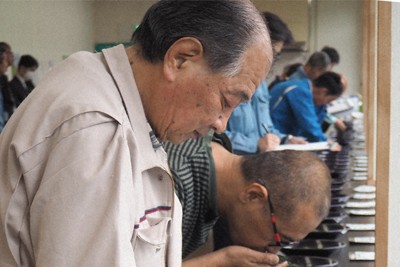 茶葉の色や香りを確認する共販会参加者ら＝岐阜県揖斐川町で2026年4月30日、入江直樹撮影