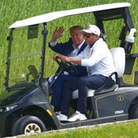 ゴルフカートから手を振るトランプ米大統領（左）＝米南部バージニア州で2026年5月9日、AP