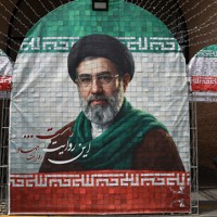 イランの最高指導者モジタバ・ハメネイ師の写真の近くを歩く女性＝テヘランで2026年5月8日、WANA・ロイター