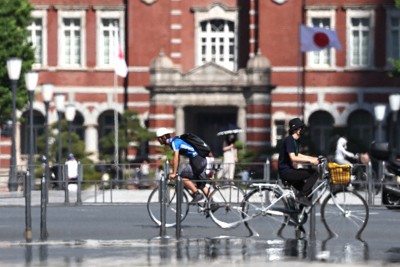 強い日差しが照りつける中、自転車で行き交う人たち＝東京都千代田区で2024年6月12日午後3時5分、玉城達郎撮影