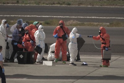 航空機への搭乗前に消毒を受けるクルーズ船の乗客たち＝スペイン・カナリア諸島テネリフェ島の空港で10日、AP