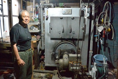 重油を使う浅草湯の風呂釜と経営者の斎藤全賢さん＝群馬県高崎市成田町で2026年5月8日、庄司哲也撮影