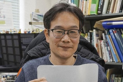廃棄うどんから生成した紙を手にする香川大の田中直孝教授＝香川県三木町で、共同