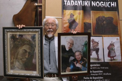 インディオを描く野口忠行さん。右手に持つのはフジモリ氏から贈られた絵、左手に持つのはフジモリ氏との最後の面会時の写真＝福岡県大川市大野島で2026年4月17日、降旗英峰撮影