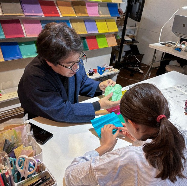 Taro Yaguchi teaches a British girl how to fold origami at his origami studio in Tokyo's Asakusa area on April 2, 2025. (Photo courtesy of Taro Yaguchi)(Kyodo)