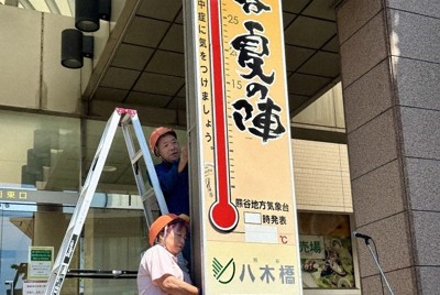 上部に新たに「酷暑日」の文字が書かれた大温度計を設置する中嶋さん夫妻＝埼玉県熊谷市の八木橋百貨店前で2026年5月14日、隈元浩彦撮影