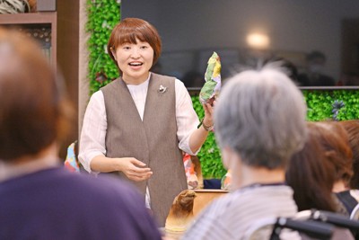 介護付き有料老人ホームでの活動で、参加者を前に説明する臨床美術士の菅原良子さん（奥）＝福岡市中央区で2026年4月15日、野田武撮影
