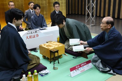 第84期名人戦七番勝負第4局2日目、対局が再開し立会の桐山清澄九段（右）が示した封じ手を見る藤井聡太名人（左）。中央は挑戦者の糸谷哲郎九段＝大阪府高槻市の高槻城公園芸術文化劇場で2026年5月17日午前8時57分、長澤凜太郎撮影
