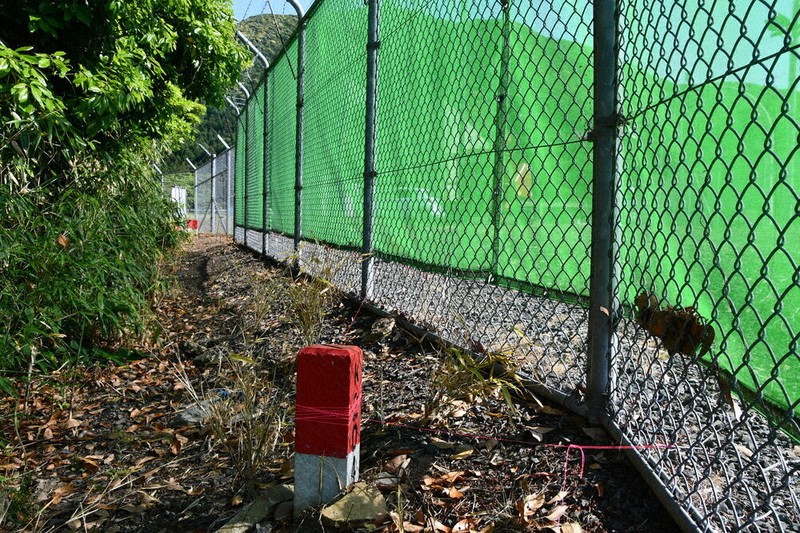 基地の境界を越えフェンスが設置されたとみられる里道には杭に赤い糸が巻き付けられていた。フェンス内部には本杭とみられる杭が設置されていた＝京丹後市丹後町の米軍経ケ岬通信所前で、塩田敏夫撮影
